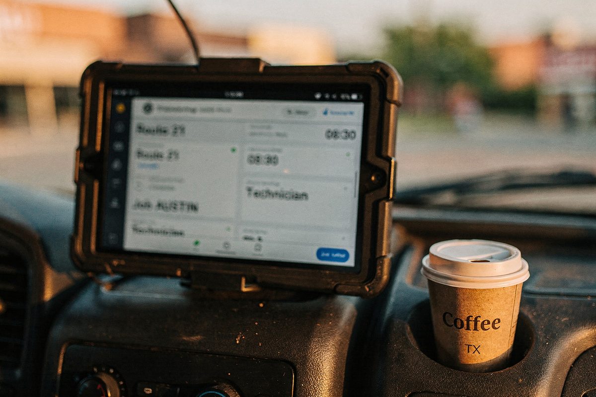 Tablet mounted on a service van dashboard showing a soft-focus dispatch schedule